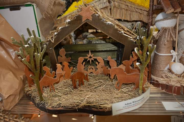 Drewniana szopka Bożonarodzeniowa. Drewniana szopka ze słomą w środku. Z drewna wycięte zwierzęta oraz postacie Święte.