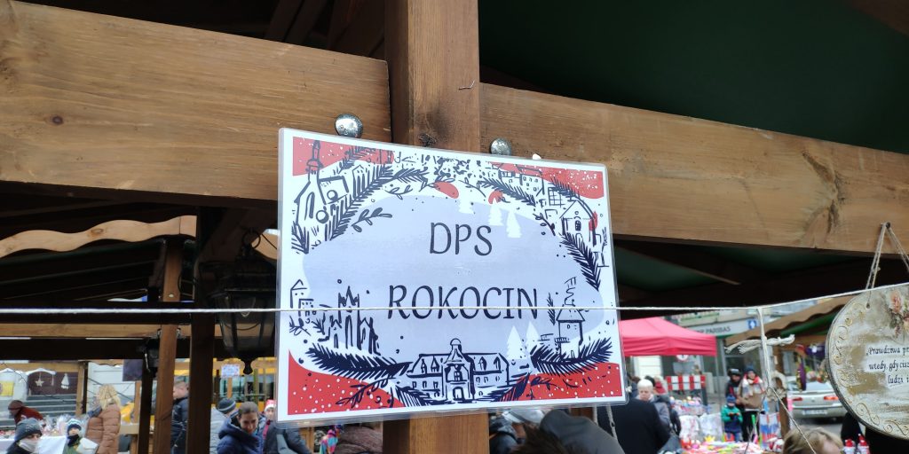 Plakietka z napisem DPS Rokocin przyczepiona do górnej belki stoiska