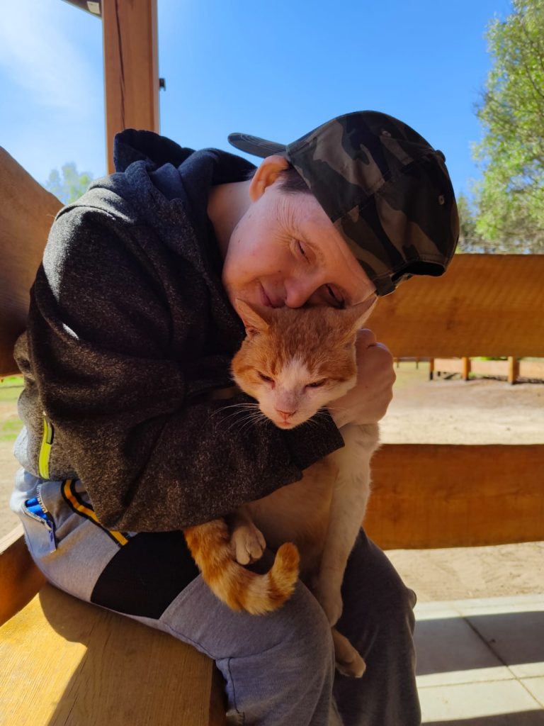 Mężczyzna przytula się do kota, którego trzyma na kolanach.