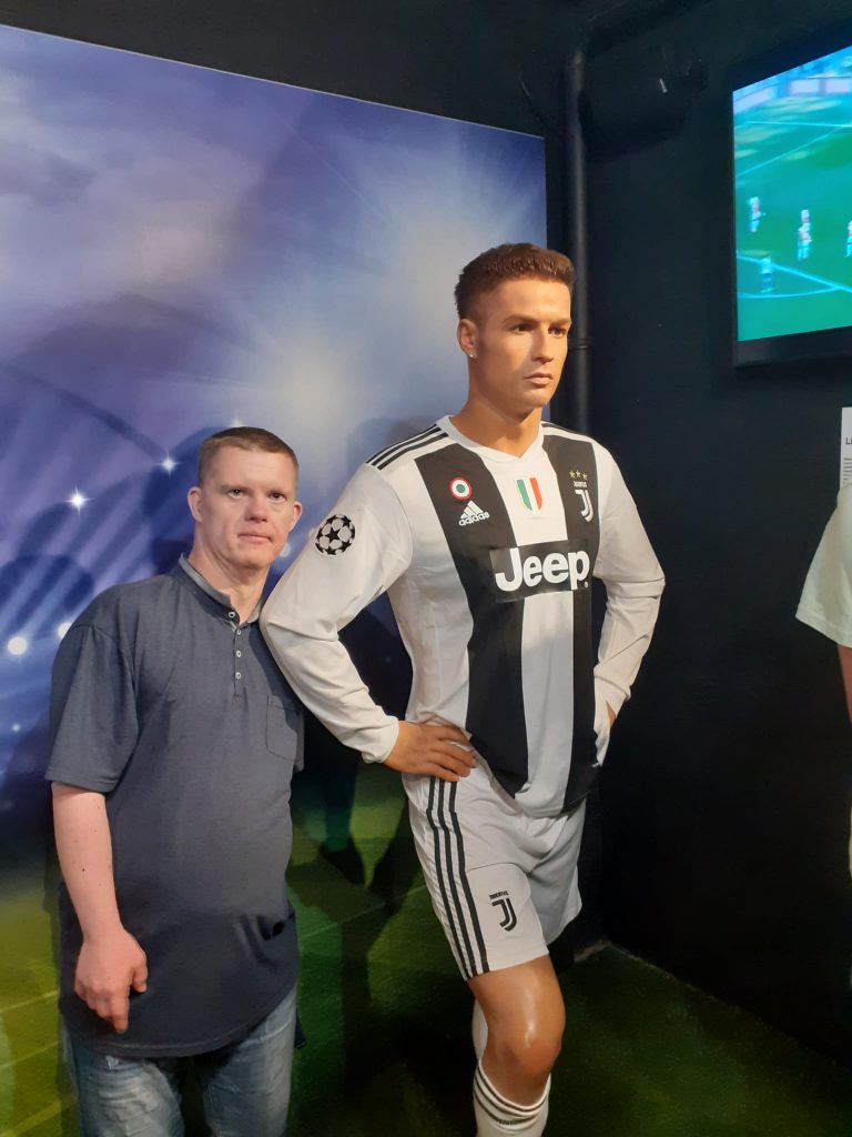 Mieszkaniec obok figury Cristiano Ronaldo ubranego w koszulkę Juventusu Turyn.