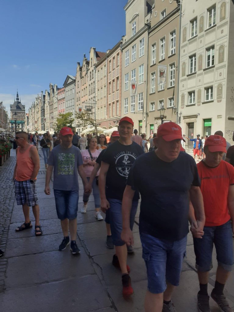 Grupa podopiecznych idąca wspólnie pomiędzy kamienicami ulicą Długą w Gdańsku.