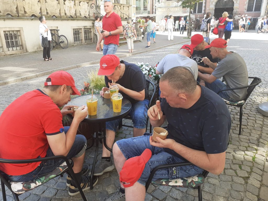 Mieszkańcy podczas jedzenia lodów oraz zimnego koktaila w barze przy jednek z uliczek w Gdańsku. W tle inni ludzie
