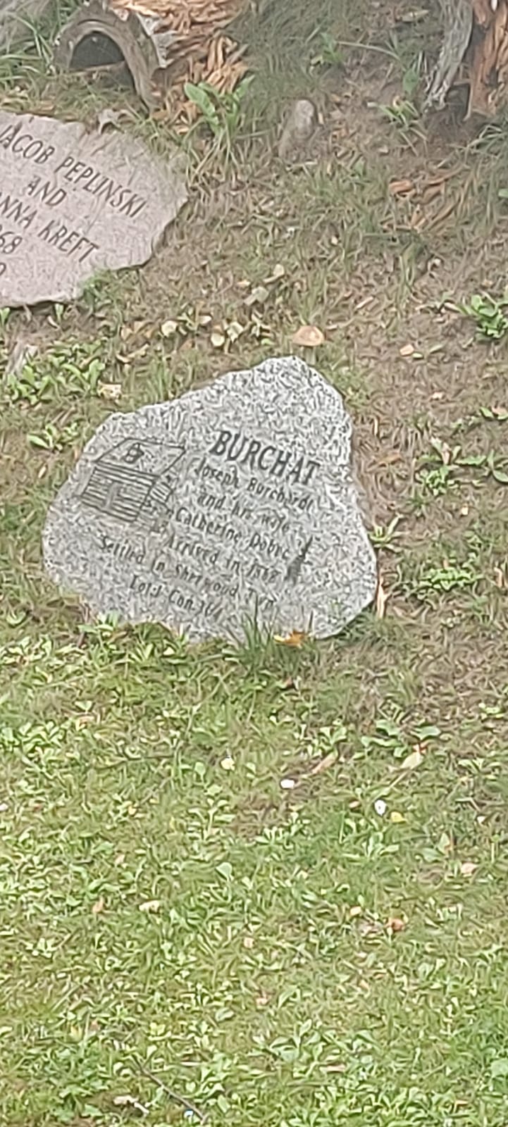 Kamienna tablica leżąca na ziemi, na niej napisy w innym języku.