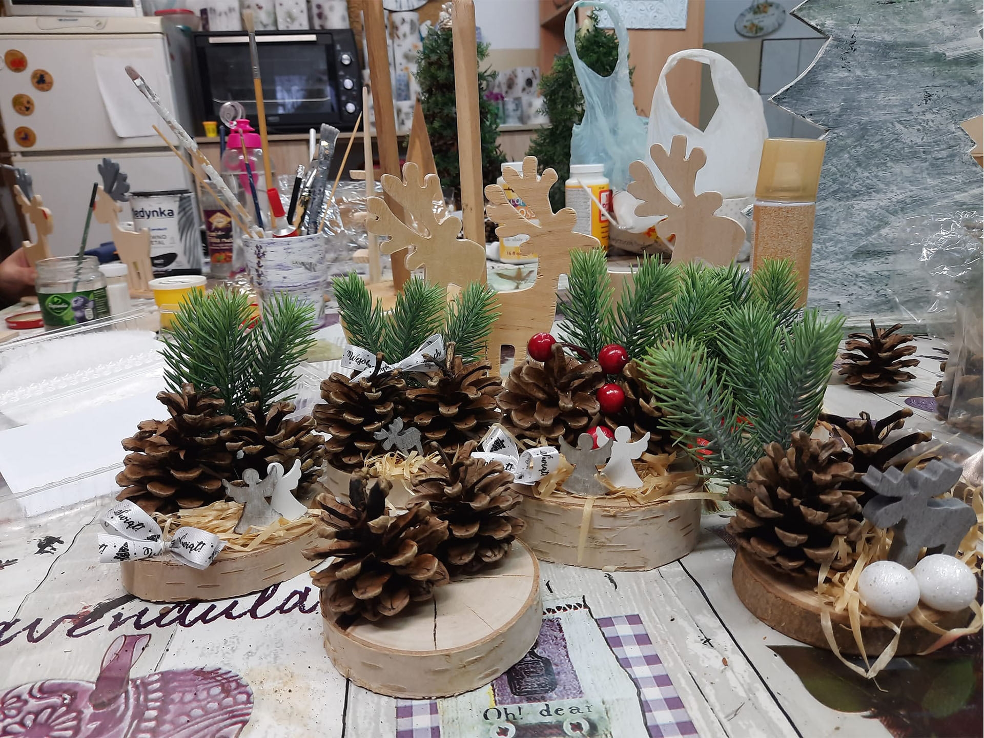 Ozdoby świąteczne leżące na stole, wykonane z naturalnych elementów tj. szyszki czy zielone gałązki.