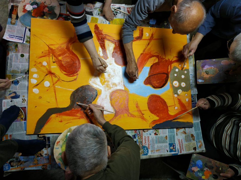 Mieszkańcy podczas malowania obrazów. Zaangażowani malują wspólnie swój obraz robiony z góry