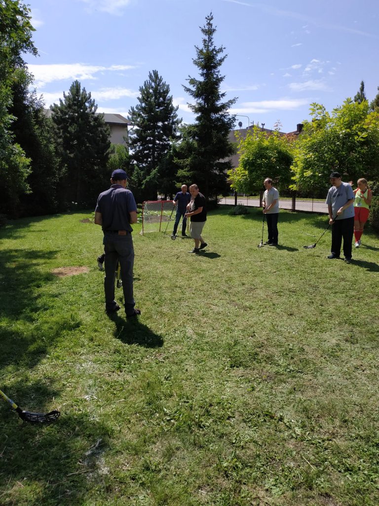 Uczestnicy Turnieju grający w unihokeja na trawie. Słonecznie i zielono wokół.
