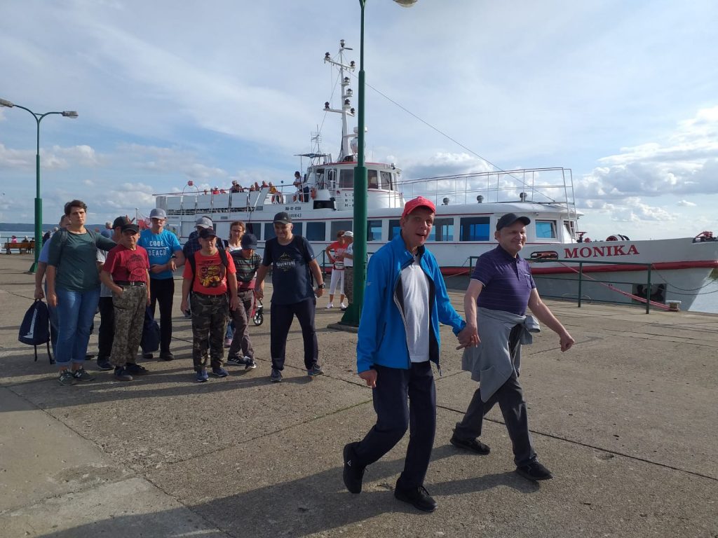 Grupa mieszkańców idących wspólnie w tle statek Monika