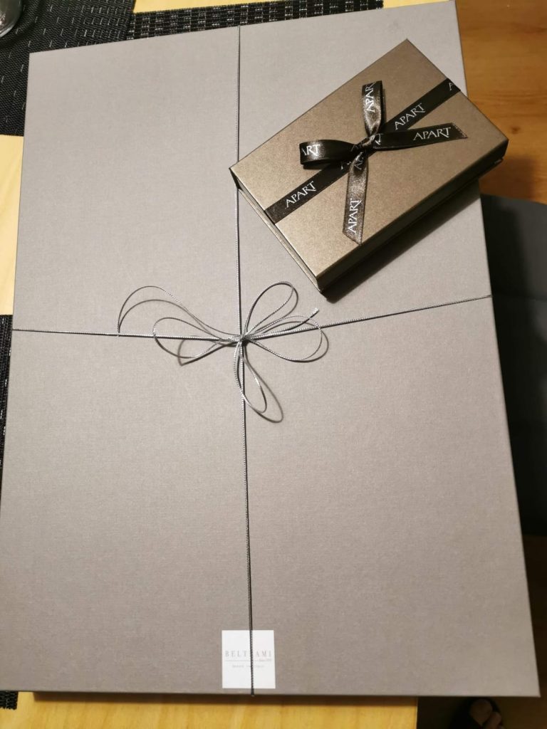 Zapakowany prezent w kartoniku tekturowym oraz mały prezencik w pudełeczku z napisem APART