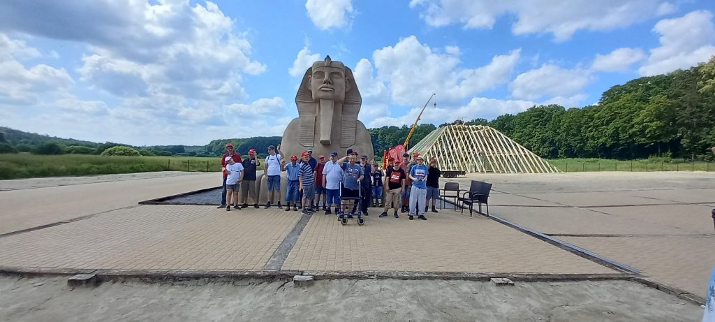 Grupa mieszkańców wraz z opiekunami pod posągiem Sfinksa