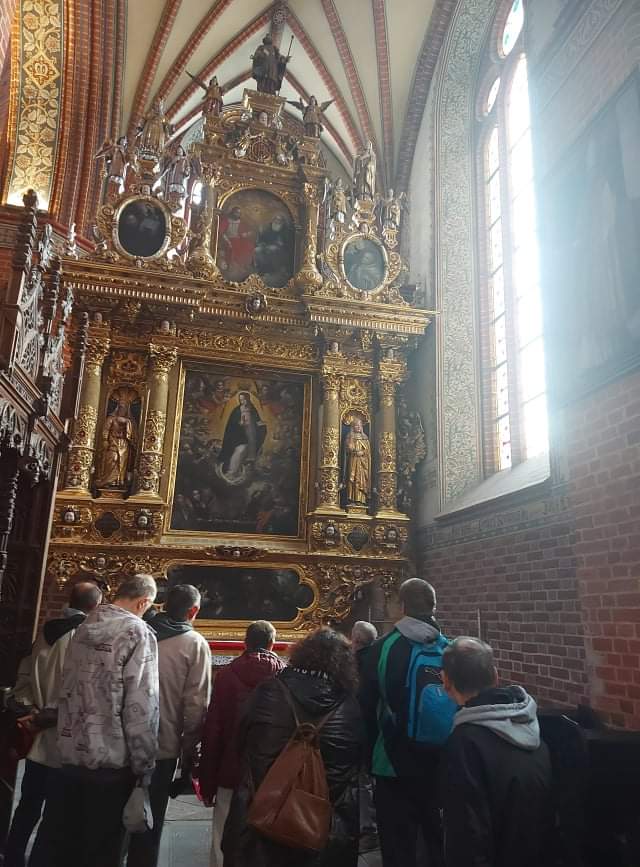 Grupa wycieczkowa stoi na przeciw wysokich pozłacanych obrazów w kapliczce pięknie zdobionej i rzeźbionej