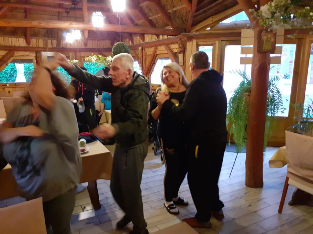 Grupa osób tańcząca w drewnianej restauracji