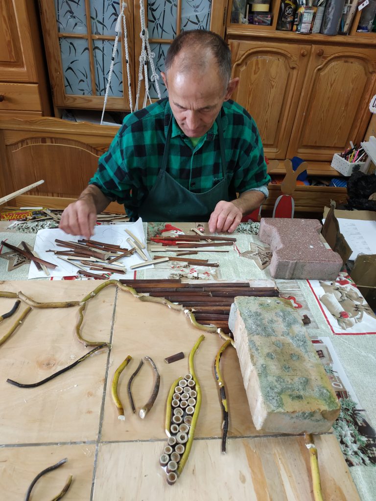 Mężczyzna siedzący przy stole układa kawałki drewnianych elementów