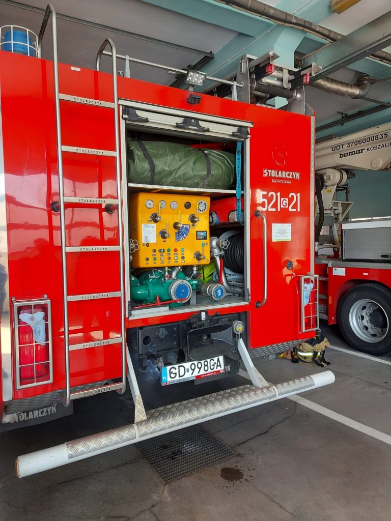 Czerwony wóz strażacki, jego tylna otwarta część widoczne pokrętła i guziki.
