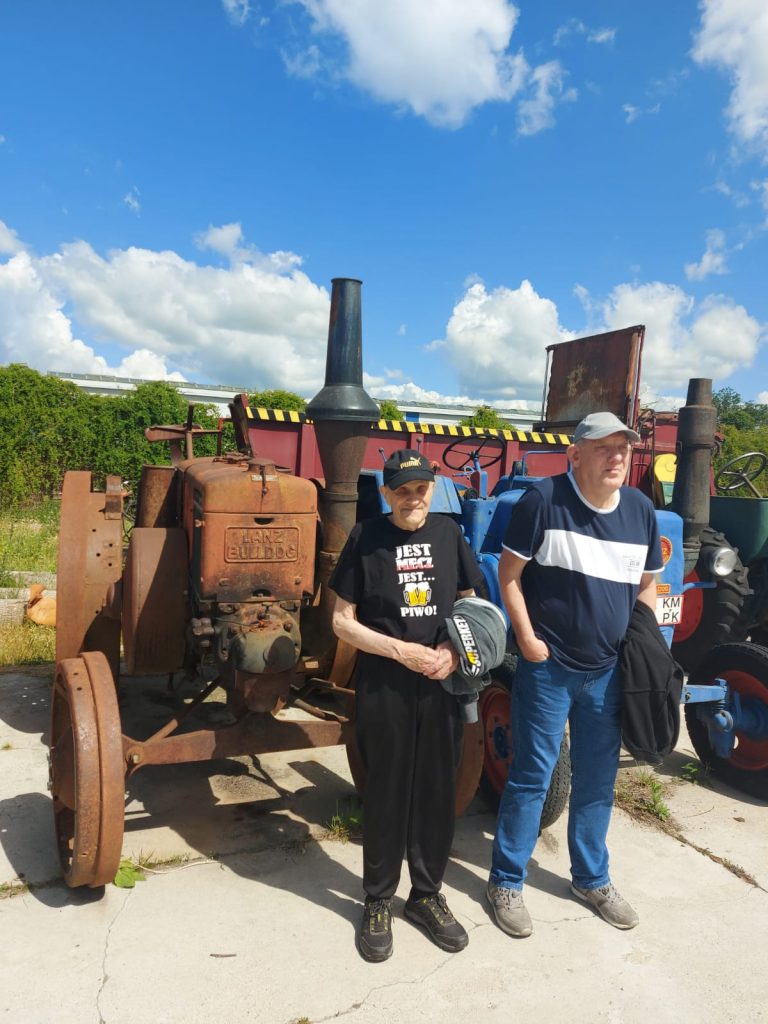 Dwóch mieszkańców stojących obok zabytkowego traktora.