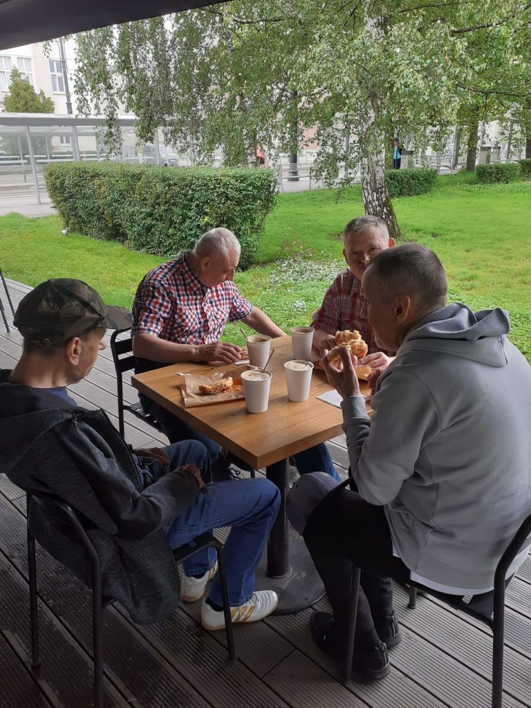 Czterech mężczyzn wspólnie jedzących posiłek i pijąc kawę.