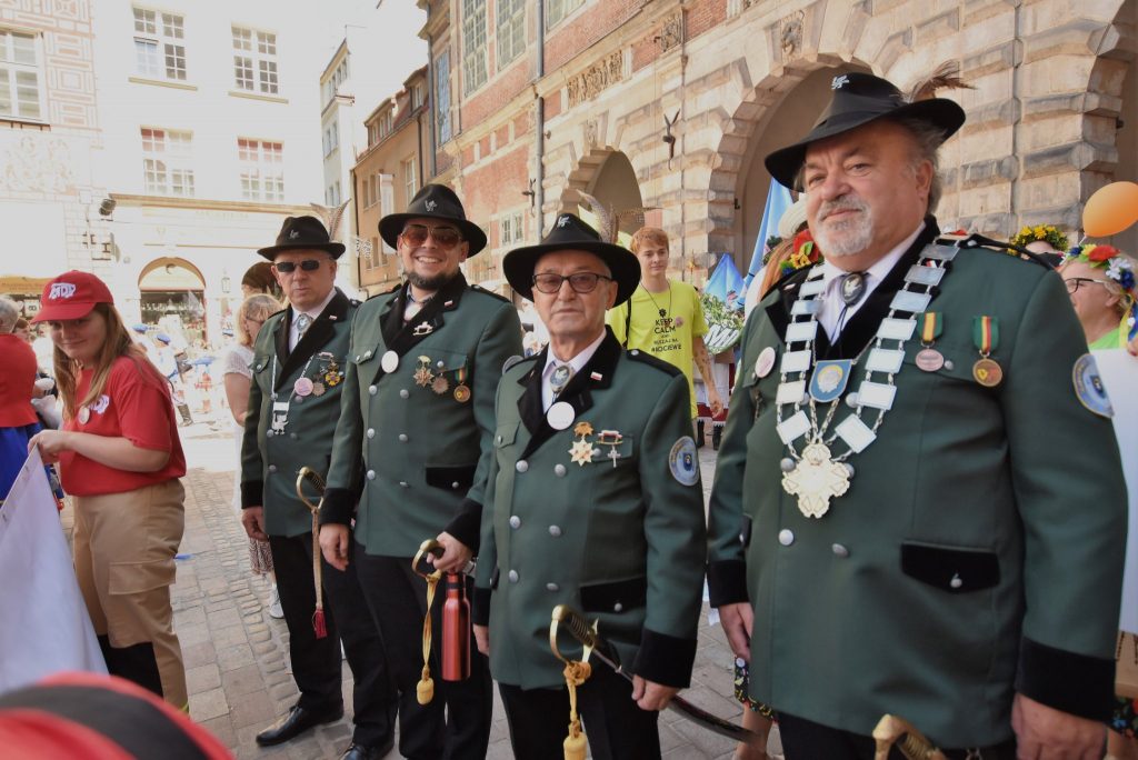 Czterech mężczyzn przebranych w zielone stroje myśliwskie (garnitury oraz kapelusze) z orderami na piersi spoglądają w stronę obiektywu.