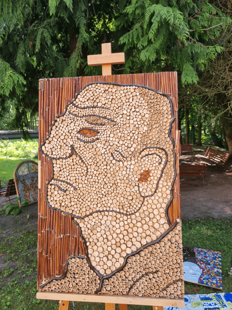 Obraz stojący na sztaludze, Przedstawia profil mężczyzny, wykonany techniką własną, płyta wiórowa, gałęzie