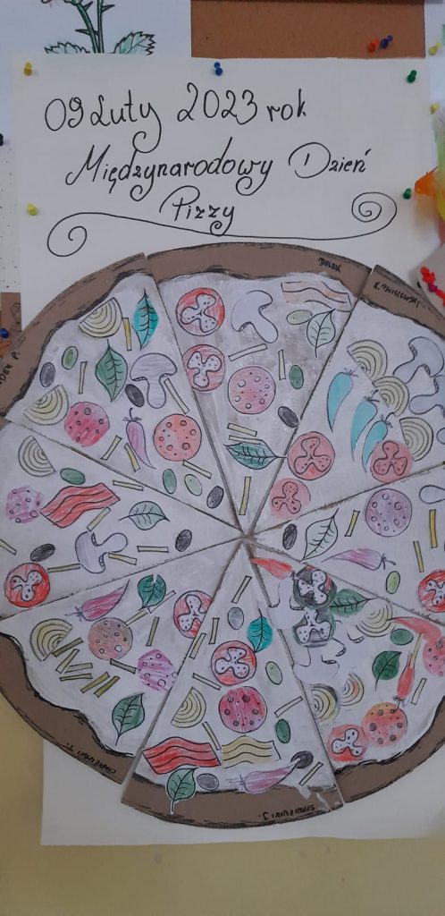 Plakat przyczepiony do tablicy przedstawia napis 09 2023 Międzynarodowy Dzień Pizzy, a pod nim pizza, która została pomalowana oraz przyklejono na nią elementy jedzenia tj. np.pieczarki, cebula, pomidor,