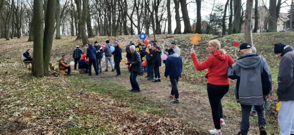 Grupa osób idąca wspólnie parkiem.